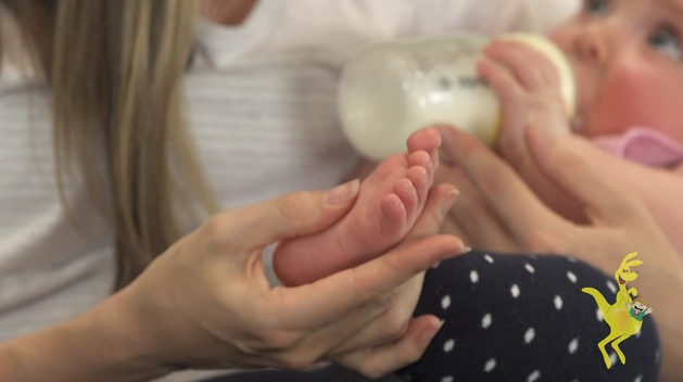 Mum massaging baby feet during feeding. GymbaROO BabyROO